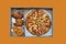 Pizza, fish rings and grilled chicken wings in paper box isolated on orange background.