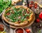 Pizza with ham, arugula and tomatoes