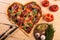 Pizza heart love Valentine`s Day romantic Italian restaurant dinner food. Prosciutto, olives, tomatoes, parsley, basil