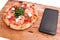 Pizza, Italian food delivery, call or order online on mobile, cellular, smart phone. Pizza and mobile phone on a wooden background