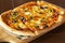 Pizza with jalapeno chillies and olives on wooden pizza board, selective focus. Dark wooden background