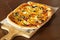 Pizza with jalapeno chillies and olives on wooden pizza board, selective focus. Dark wooden background