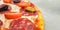 Pizza macro with selective focus. Fresh homemade tasty pepperoni with salami, olives and cherry tomato