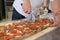 Pizza maker cutting focaccia romana