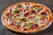 Pizza with Mozzarella cheese, ham, tomato sauce, salami, pepper, Spices and Fresh arugula. Italian pizza on wooden table