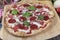 Pizza with Mozzarella cheese, ham, tomato sauce, sausage sucuk , pepper, Spices and Fresh arugula. Italian pizza on wooden table