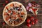 A pizza with mushrooms, salami, pepperoni and olives lies on a rustic table alongside red peppers, tomatoes, cheese and sausage