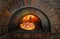 Pizza near the stone stove with fire. Traditional italian pizzeria restaurant.