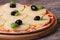 Pizza with pineapple, black olives and green basil