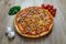 Pizza with red sauce, ham, mozarella, corn, onion rings, red bell pepper, mushroom top angle