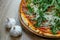 Pizza with red sauce, serrano ham, arugula and shredded mozzarella detail