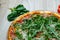 Pizza with red sauce, serrano ham, arugula and shredded mozzarella detail