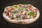 Pizza with roast beef and artichokes, jalapenos, chili, mozzarella, pesto. Neapolitan round pizza on wood background