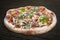 Pizza with roast beef and artichokes, jalapenos, chili, mozzarella, pesto. Neapolitan round pizza on wood background