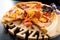 Pizza with sausage and tomatoes on a wooden round tray with a carved inscription `Pizza`.