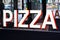 Pizza sign in white, black and red letters on restaurant glass