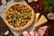 Pizza still life. Freshly baked pizza and its components arranged on wooden background.