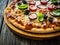 Pizza with white mushrooms, sausage, tomatoes, black olives, parmesan and mozzarella on wooden background