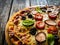 Pizza with white mushrooms, sausage, tomatoes, black olives, parmesan and mozzarella on wooden background