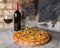 Pizza with wine and oil on a firebricks background