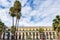 Placa Reial, shaded by palms and decorated by Gaudi street lights. Detail of the side palace. Barcelona