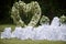 Place decorated for the wedding ceremony with heart arch from white flowers. Outdoors setup