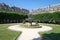 Place des Vosges with fountain in Paris in a sunny morning, clear blue sky
