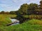 Place for fishing on creek. Summer background with forest on riverbank