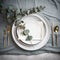 Place setting for dinner. Elegant table decorated with eucalyptus branches.