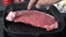 Placing a rib steak on a cast iron grill to cook
