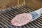 Placing a seasoned hamburger on a hot grill