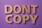 Plagiarism concept. Phrase Don`t Copy made of wooden letters on violet background, top view