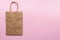 Plain blank brown paper bag on a pink background left, empty for own design