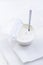 Plain Greek Yogurt in cup with spoon on white