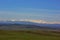 Plain, green fields on the background of snow capped peaks of Caucasus mountains