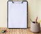 Plain Office Clipboard With Stack Of Pens In A Holder On Top Of A Table. Empty Paper Sheet With Colorful Pencils