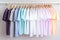 Plain t-shirts of different pastel colors hanging on wooden clothes hanger