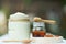 Plain yoghurt in white bowl, honey, cereal, raisin and wood spoon on white wooden table background