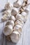 Plait of white garlic on white wooden background