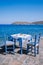 Plaka Lassithi with is traditional blue table and chairs and the beach in Crete Greece