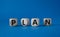 Plan symbol. Concept word Plan on wooden cubes. Beautiful blue background. Business and Plan concept. Copy space