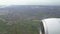 Plane engine seen through window, green fields below flying aircraft, travel