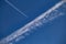 A plane flies in the blue sky leaving a white trail