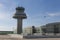 A plane flies next to the control tower at Barcelona Airport, Sp