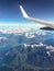 The plane flies in the sky over the mountains. airplane wing above the clouds. top view of the mountains.