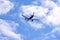 Plane flying in the blue sky amid clouds and sunlight, travel by air