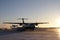 A plane getting ready for takeoff in the late morning with orange sunrise