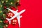 Plane, gift box, Christmas decoration on red background. Christmas travel concept. Christmas background avia travel.