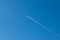 A plane leaves a white contrail across the clear blue sky, a sign of travel and distant journeys.