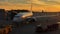 Plane near the terminal at the airport at sunset or sunrise, loading or unloading things from the plane a